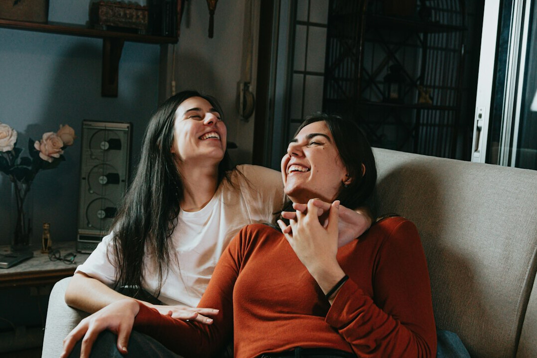 Duas pessoas sorrindo durante uma conversa leve em um espaço aconchegante