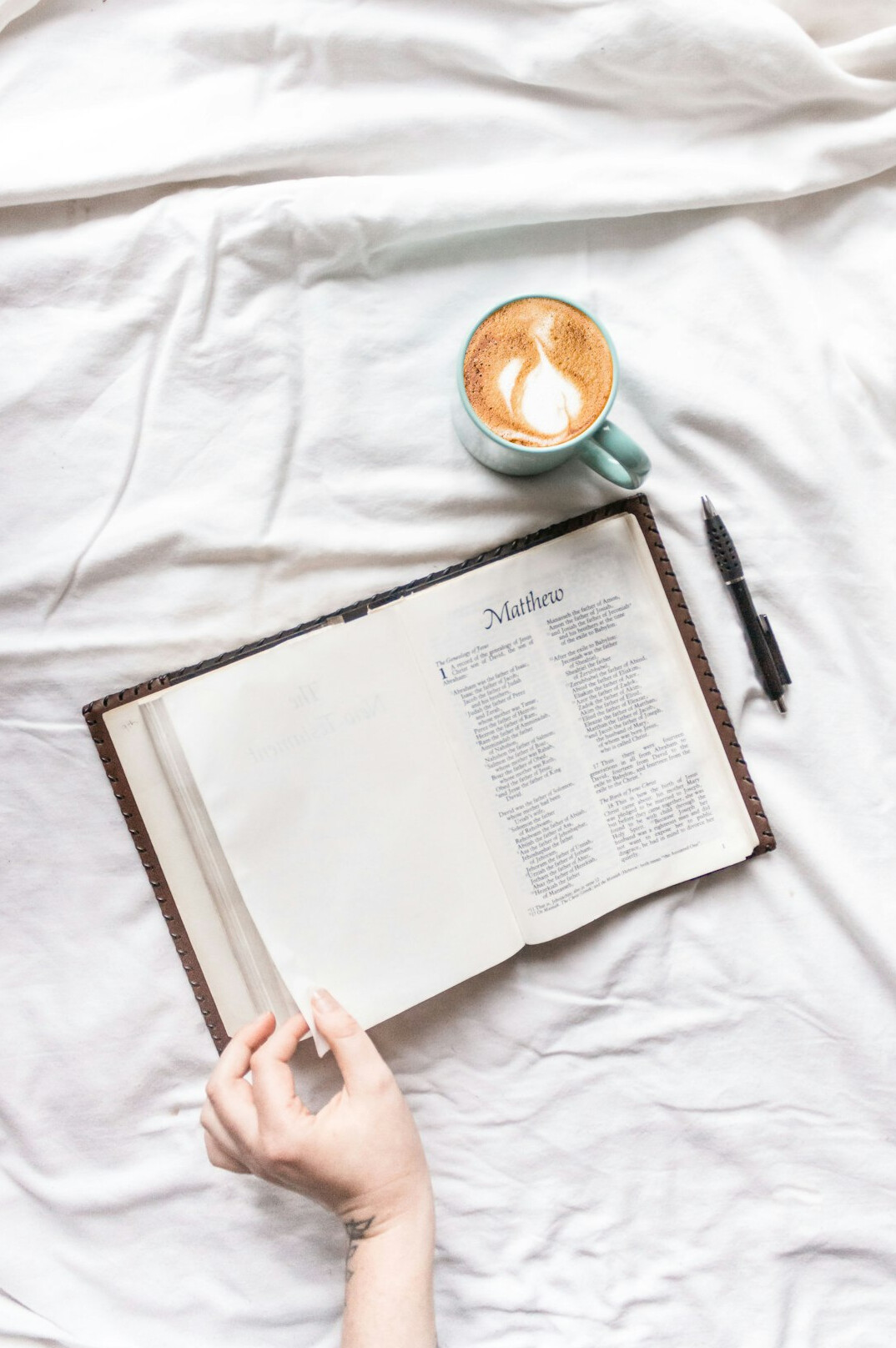Mãos escrevendo em um caderno aberto ao lado de uma xícara de café